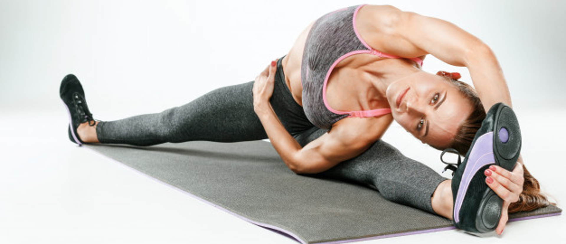 Woman athlete stretches sitting in straddle